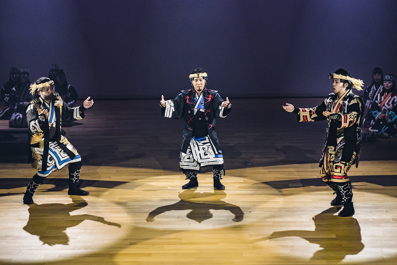 ウポポイのホールで舞踊を行うアイヌ伝統衣装のスタッフ3人